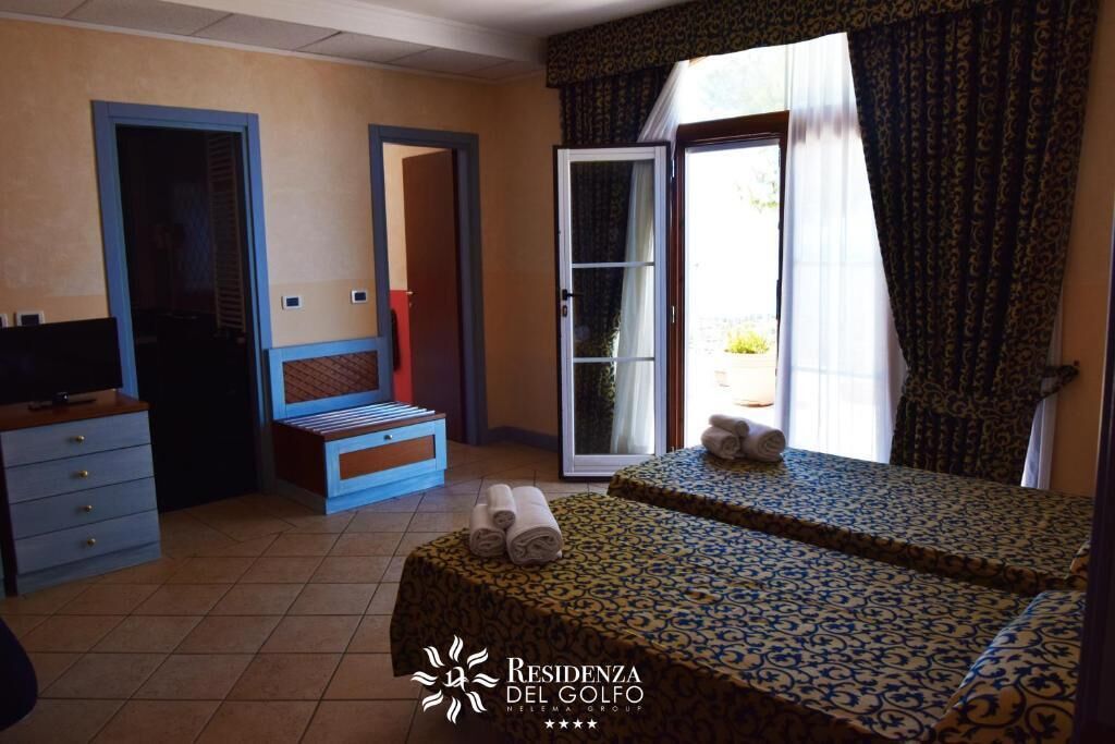 Camera d'albergo con due letti, una scrivania, una sedia e una televisione.