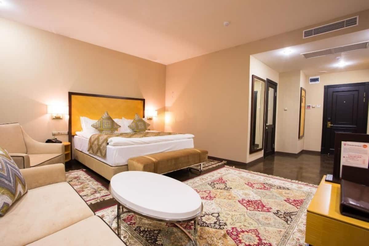 A hotel room with a bed, a chair, a small table, and a patterned rug.