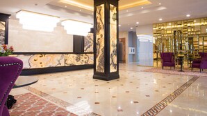 A lobby with a marble reception desk, a tall pillar, and purple seating. - Best Western Plus Astana (Astana)