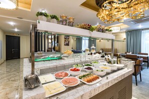 Un bufé con diversos alimentos y una zona de estar con mesas y sillas.