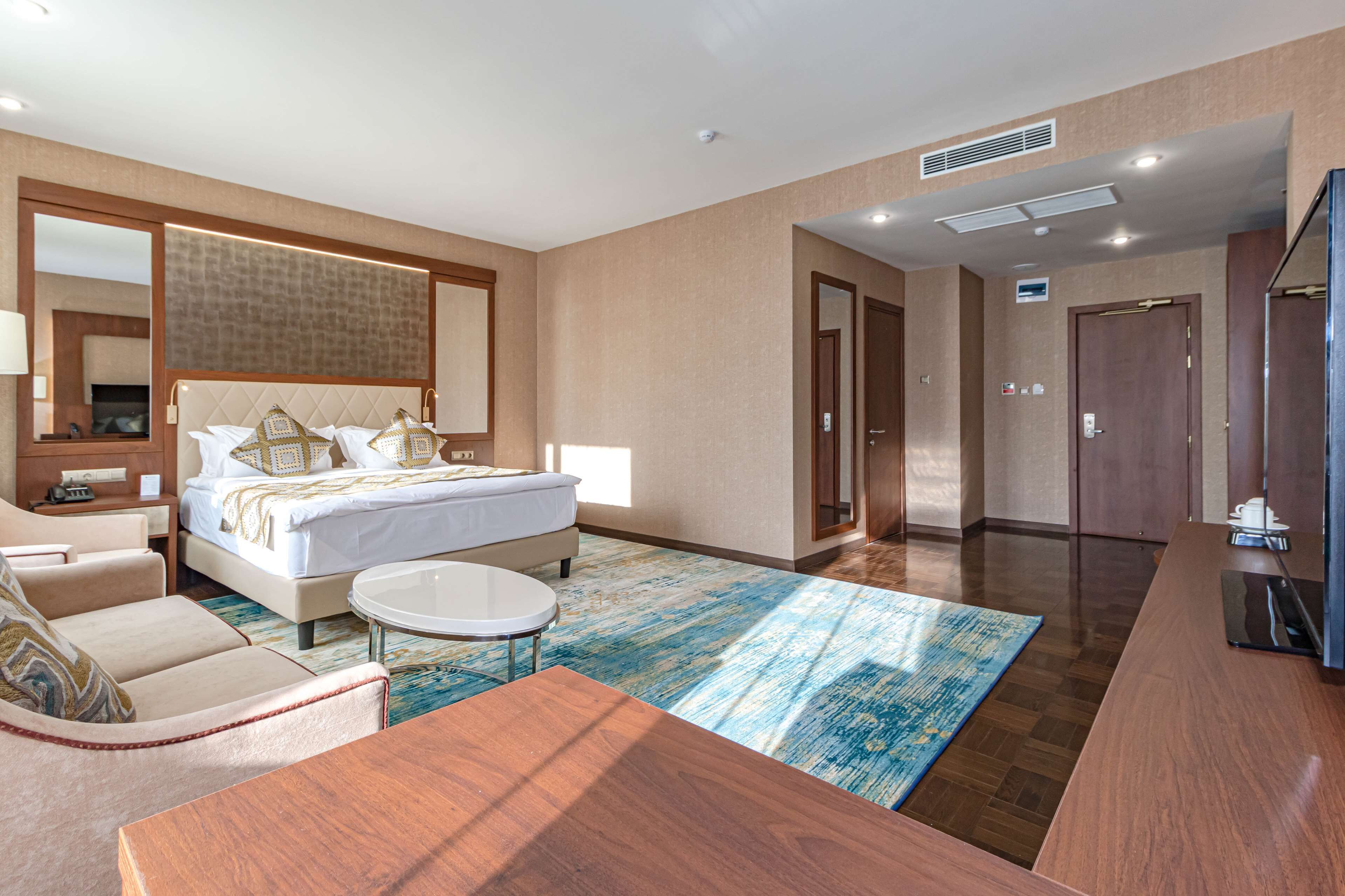 A hotel room with a bed, a desk, a chair, a TV, and a bathroom.
