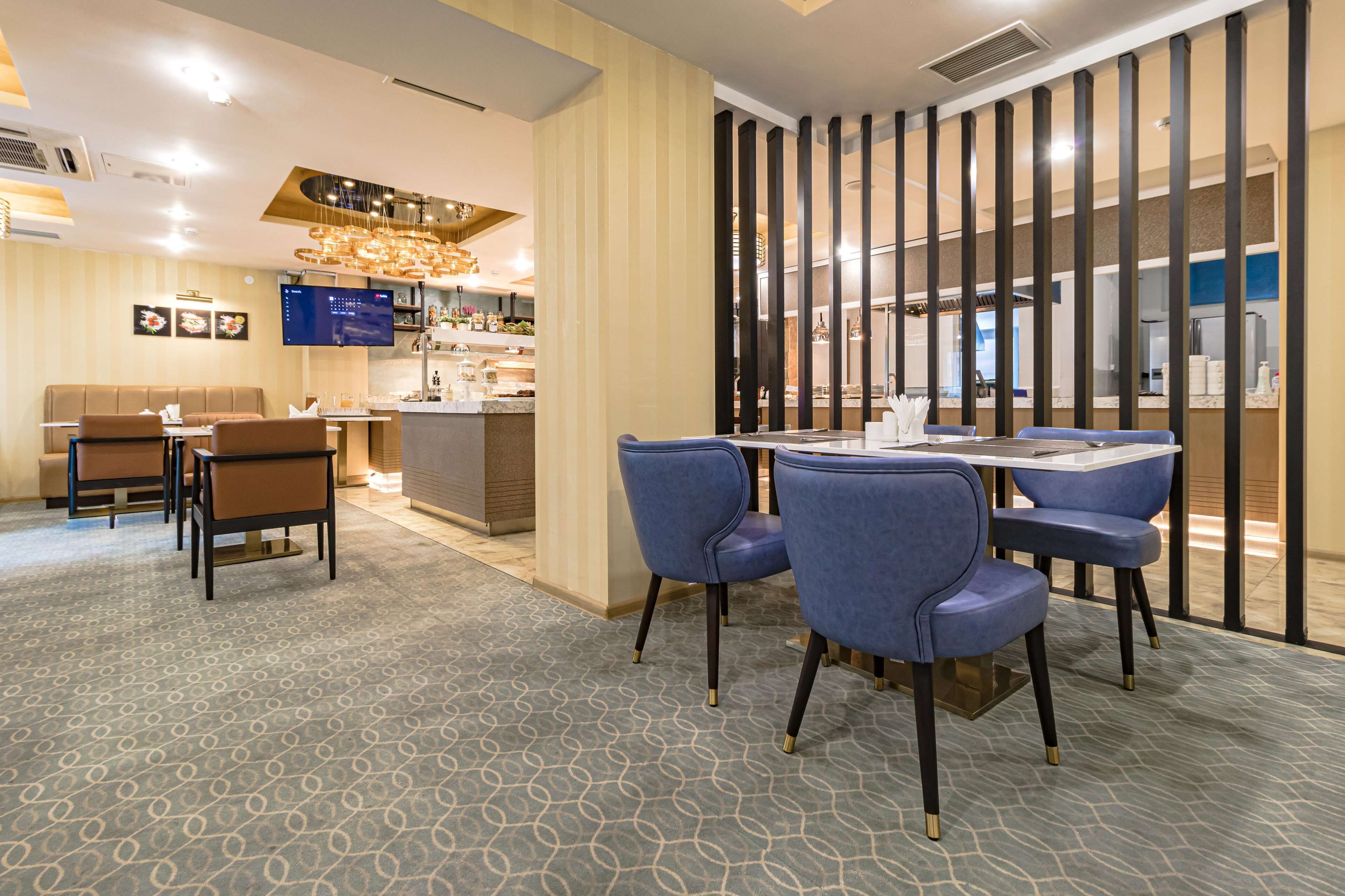 A modern dining area with a bar, blue upholstered chairs, and a patterned carpet.