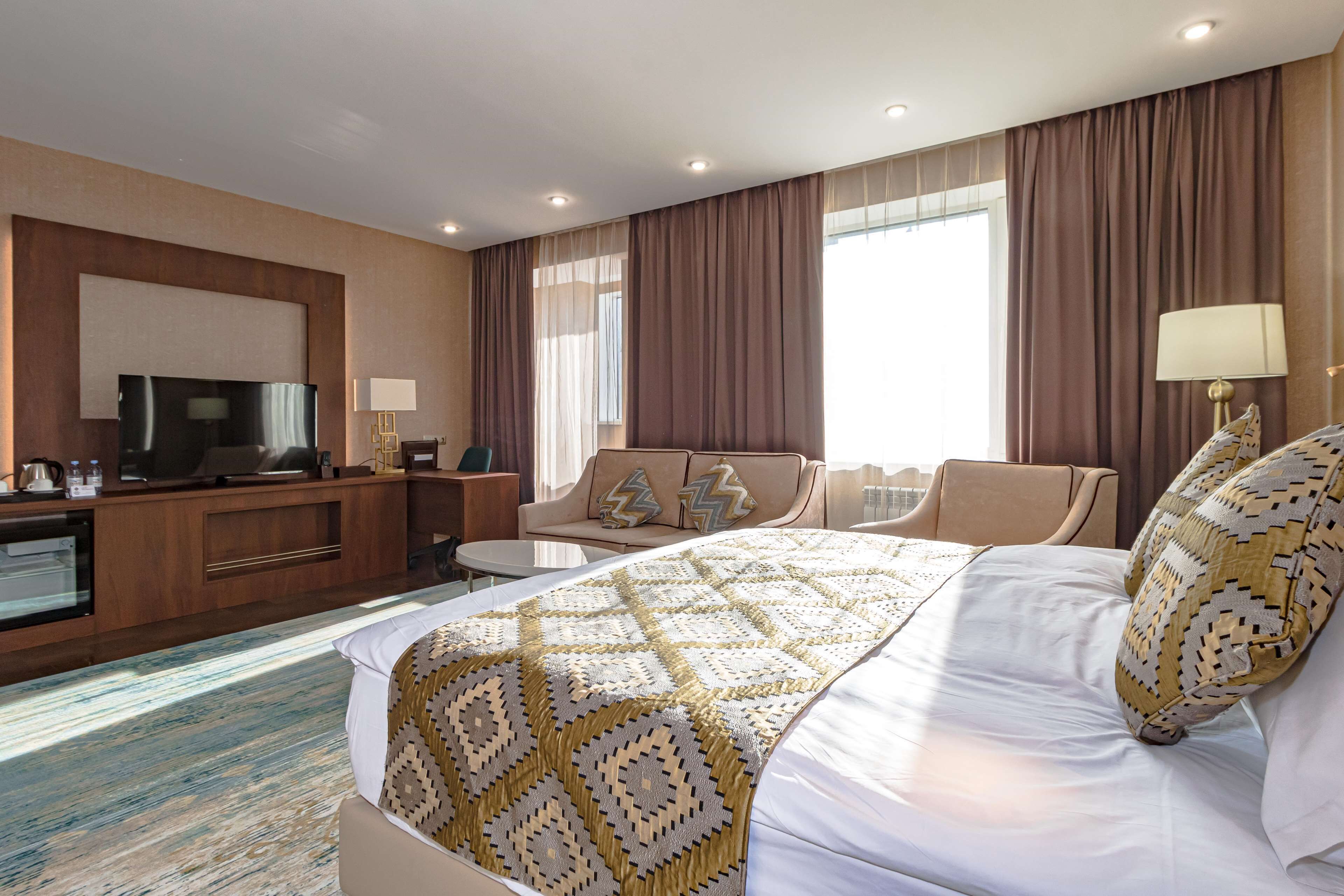 A hotel room with a bed, a TV, a desk, and a sofa.