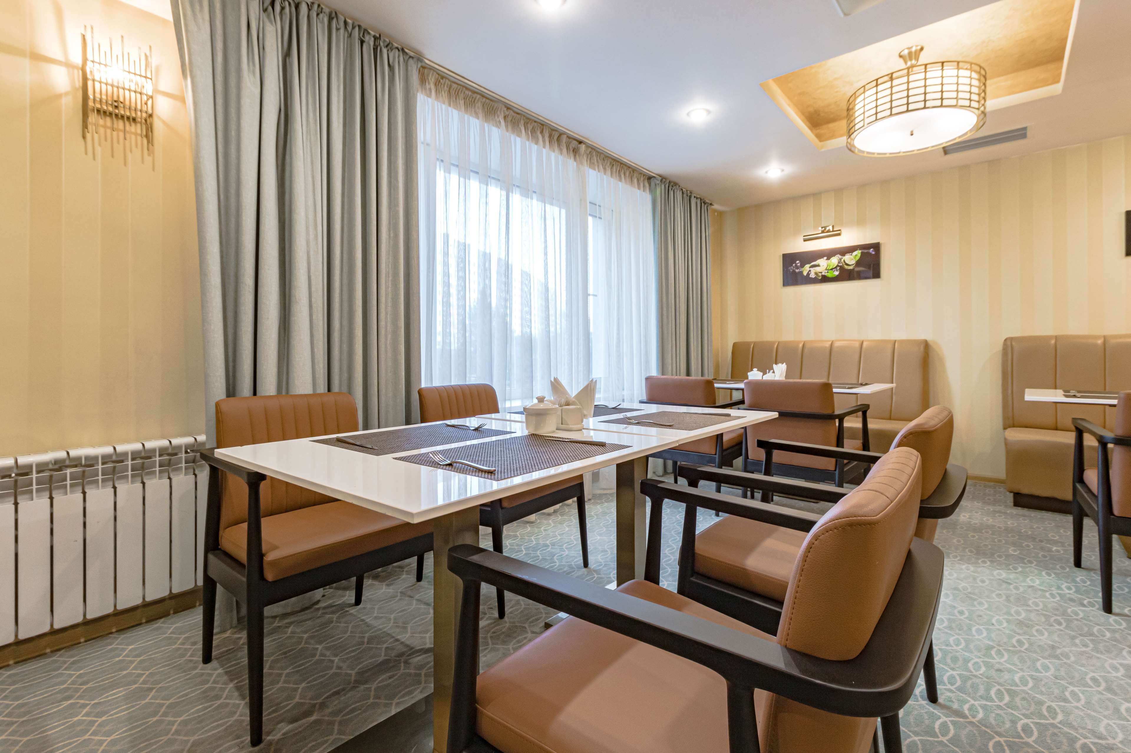 Un salón de conferencias de hotel con una larga mesa, múltiples sillas y una zona de sofás.