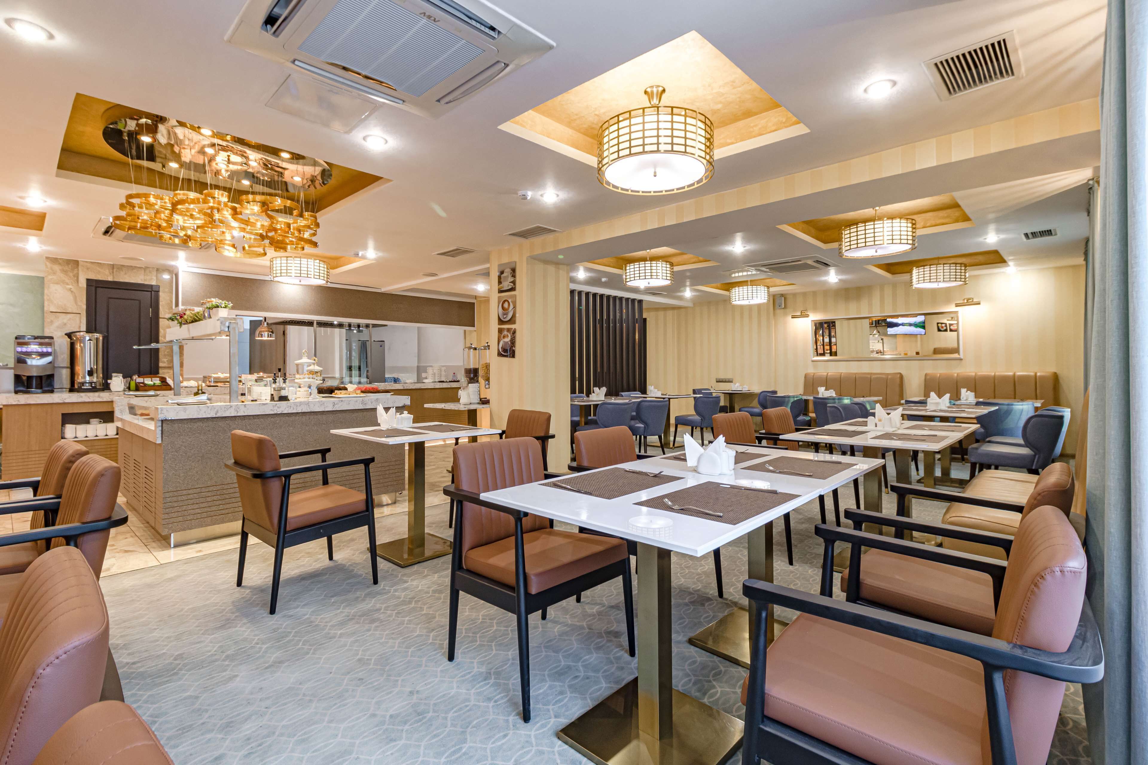 Un restaurante moderno con barra central, numerosas mesas y lámparas de diseño contemporáneo.