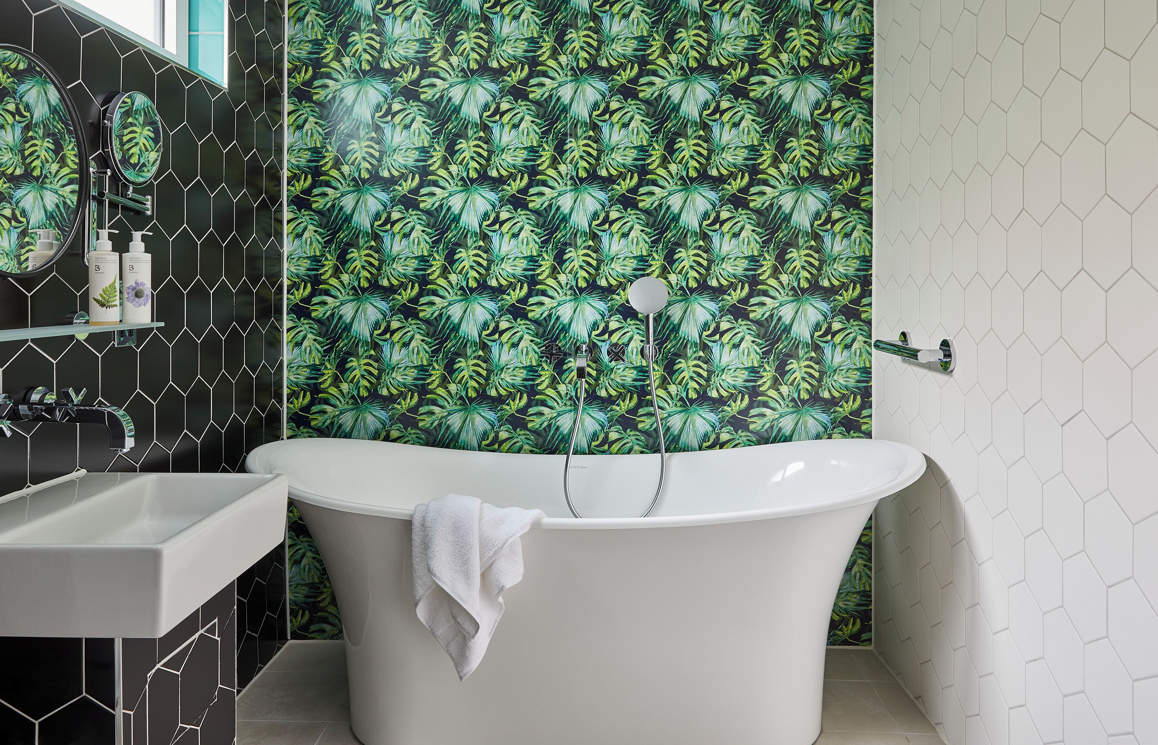 Een badkamer met een vrijstaand bad, een spiegel en een plank met toiletartikelen.