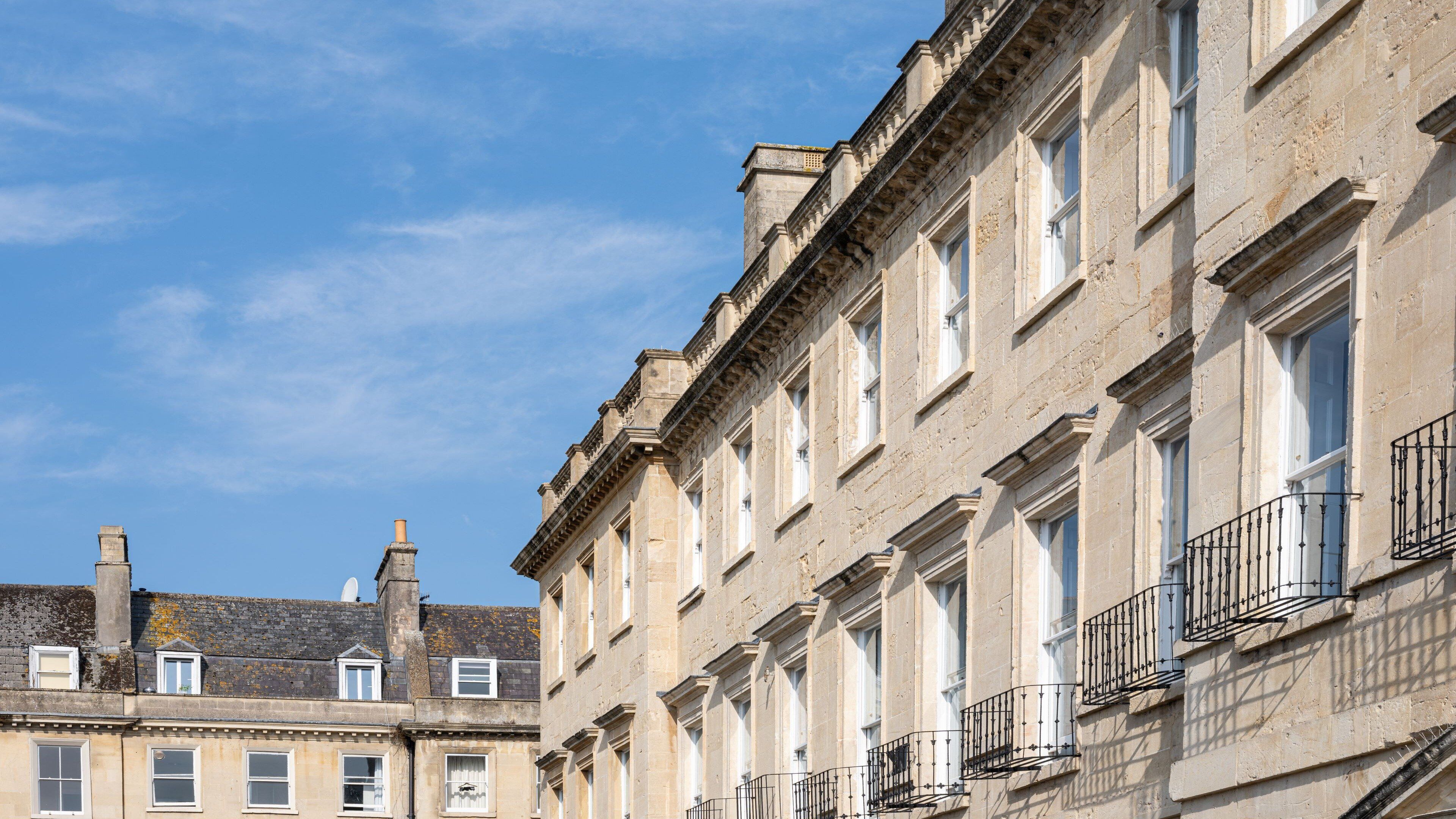 A row of historic buildings with uniform architectural style, featuring multiple windows and balconies.