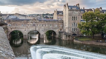 A historic stone bridge over a river with a water feature in the foreground.