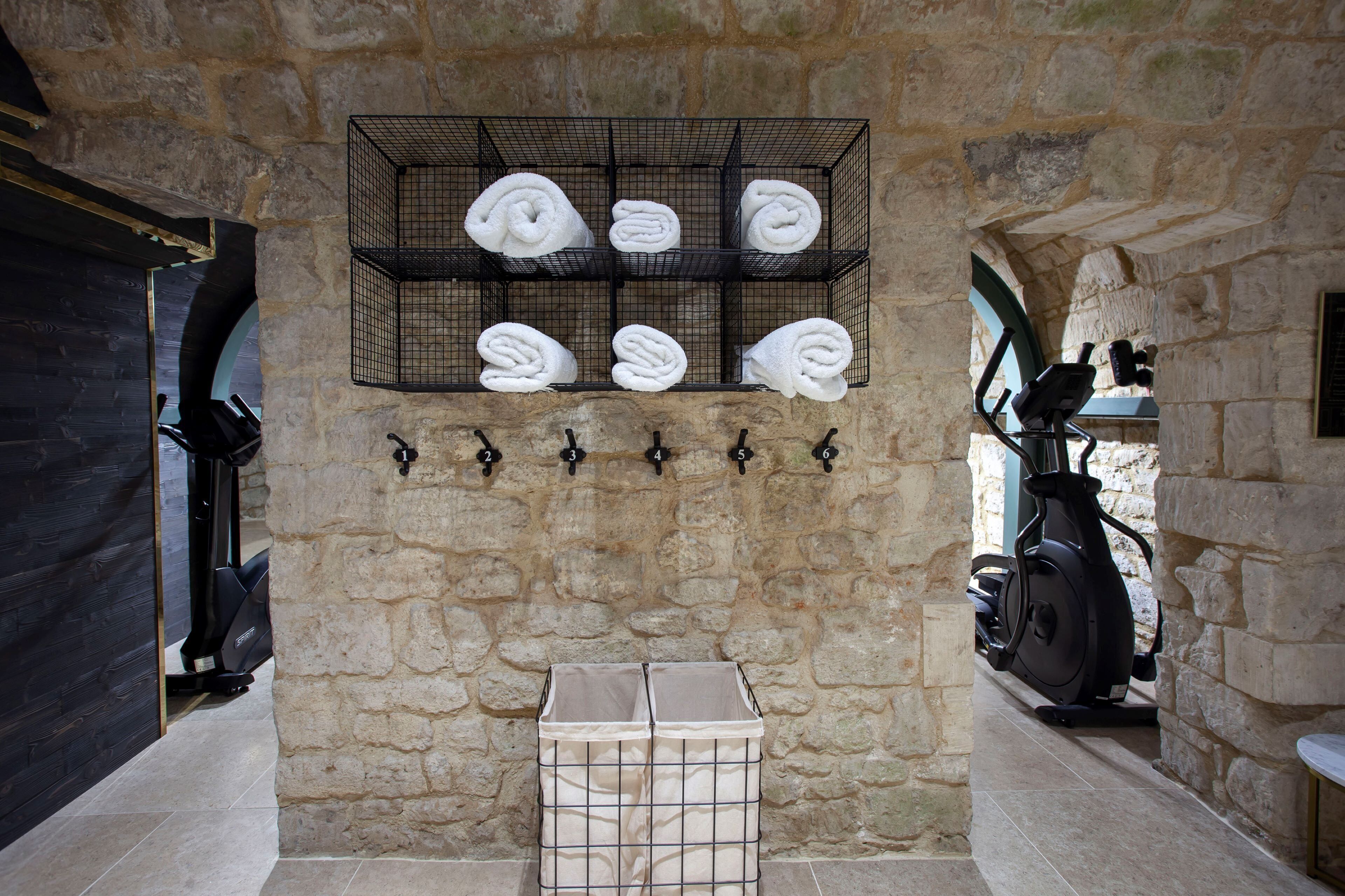 A stone-walled room with a rack holding towels, a storage box, and exercise equipment.