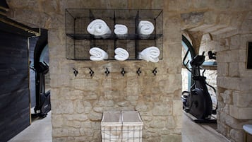 A stone-walled room with a rack holding towels, a storage box, and exercise equipment.