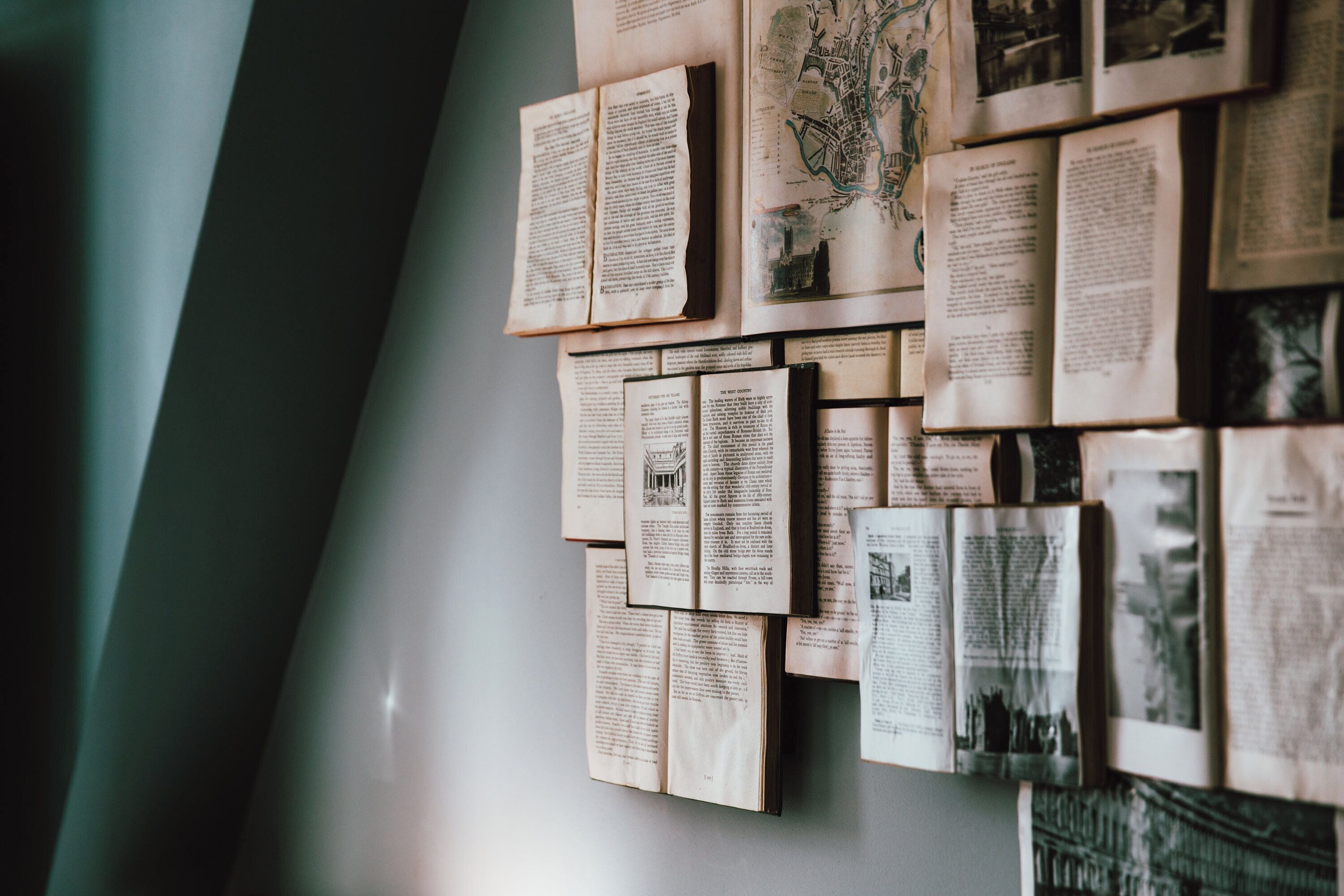 Una pared cubierta de diversos documentos y fotografías, entre ellos mapas y texto.