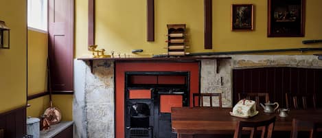 A room with a fireplace, wooden furniture, and a table with a teapot and a decorative item.
