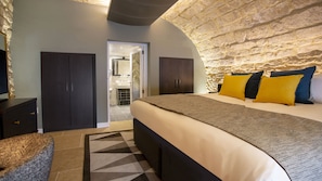 A bedroom with a large bed, dark wooden wardrobe, and a stone accent wall. - Hotel Indigo Bath by IHG (Bath)
