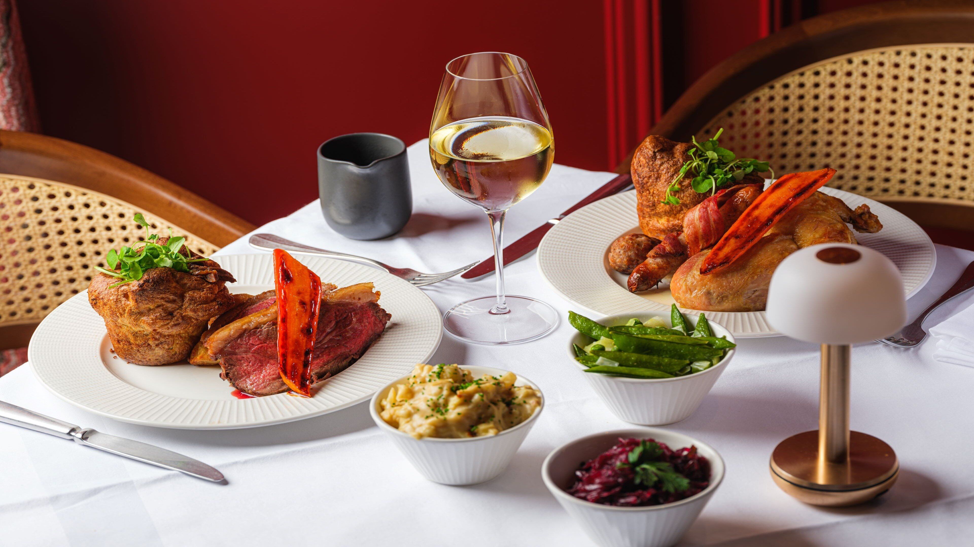 A table set with plates of food, a wine glass, and a lamp.