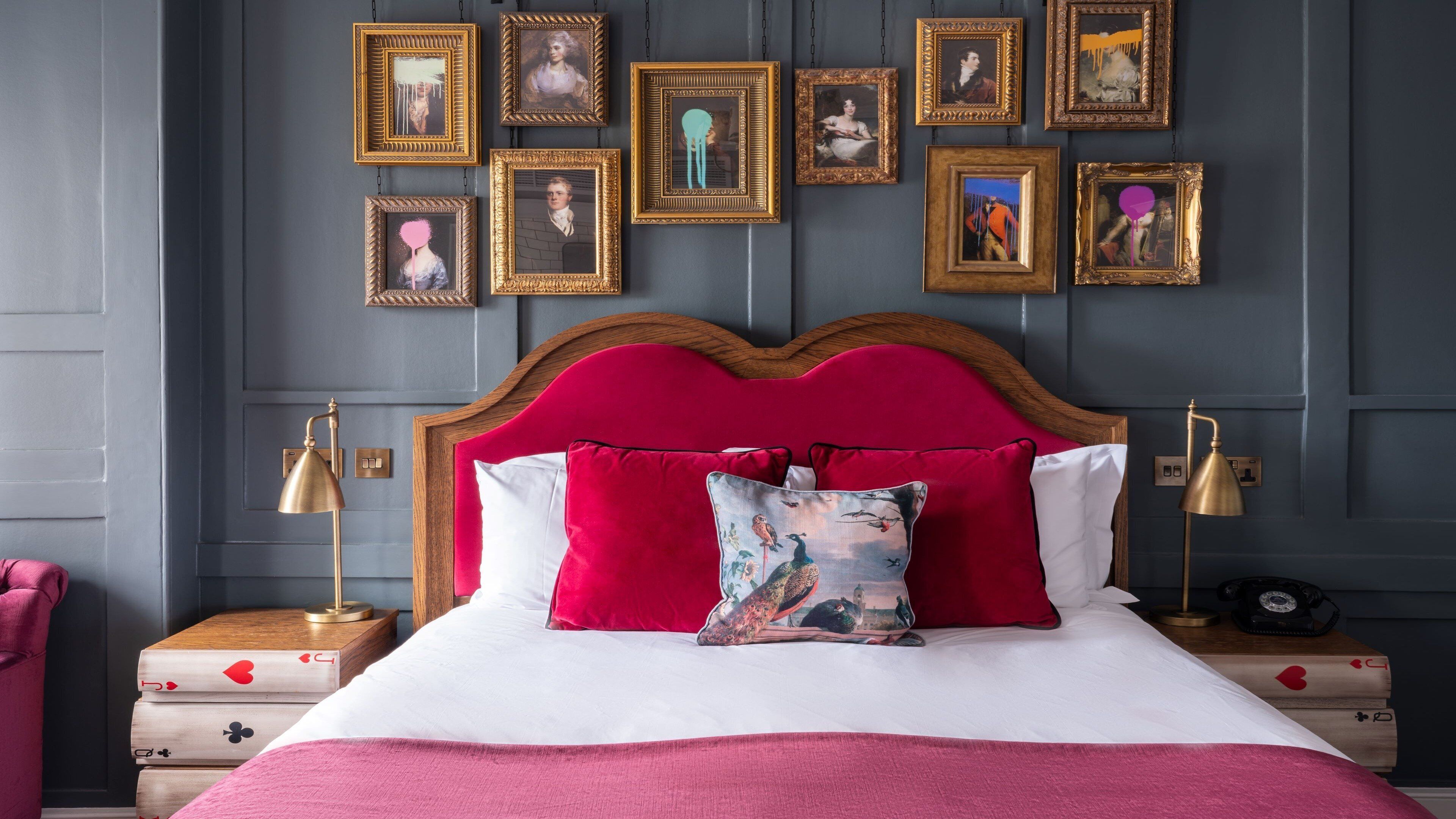 A bedroom with a wooden headboard, white bedding, and multiple framed pictures on the wall.