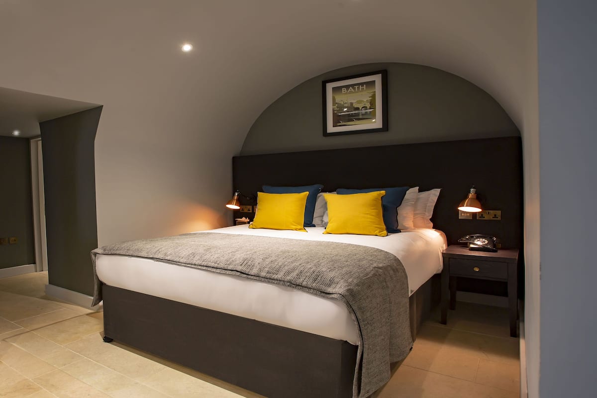 A bedroom with a bed, nightstands, a dresser, and a framed picture on the wall.