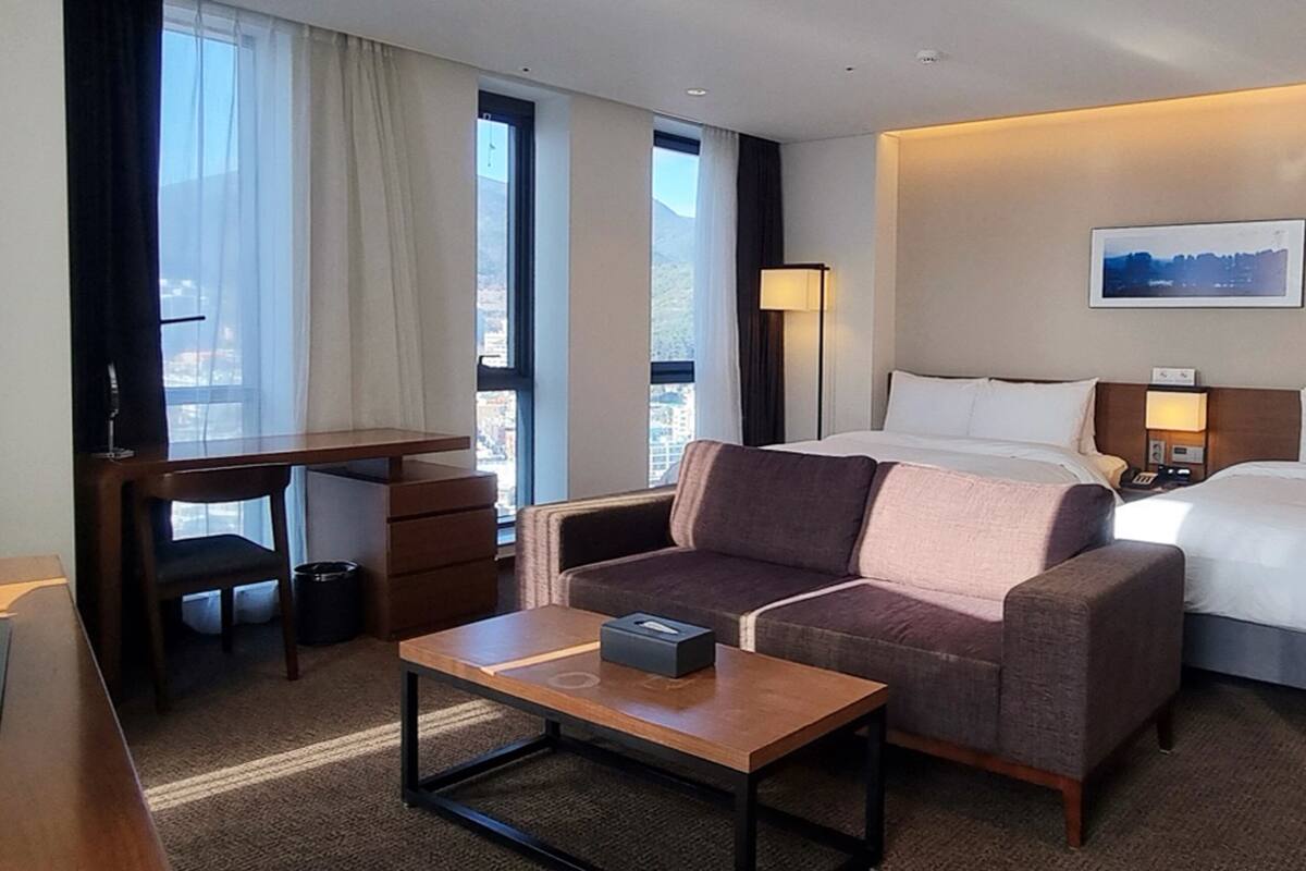 A hotel room with a bed, a sofa, a desk, and a television.