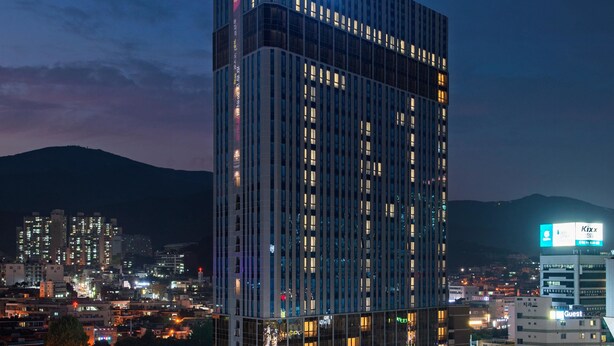 A high-rise hotel with a prominent 'Encore' sign, multiple floors, and a cityscape in the background. - Ramada Encore by Wyndham Haeundae (Busan)