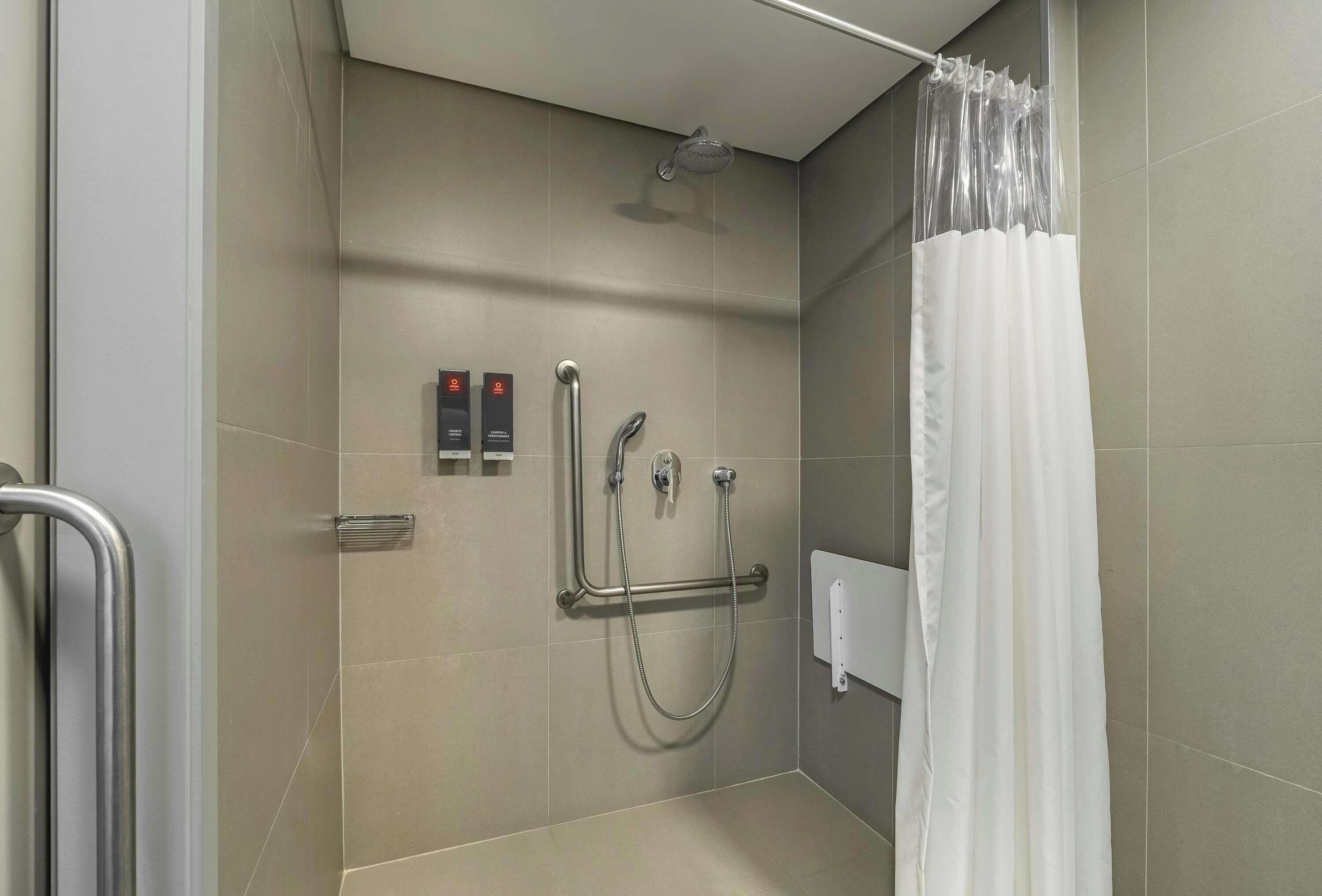 A modern shower area with a handheld showerhead, a handheld shower attachment, and a grab bar.
