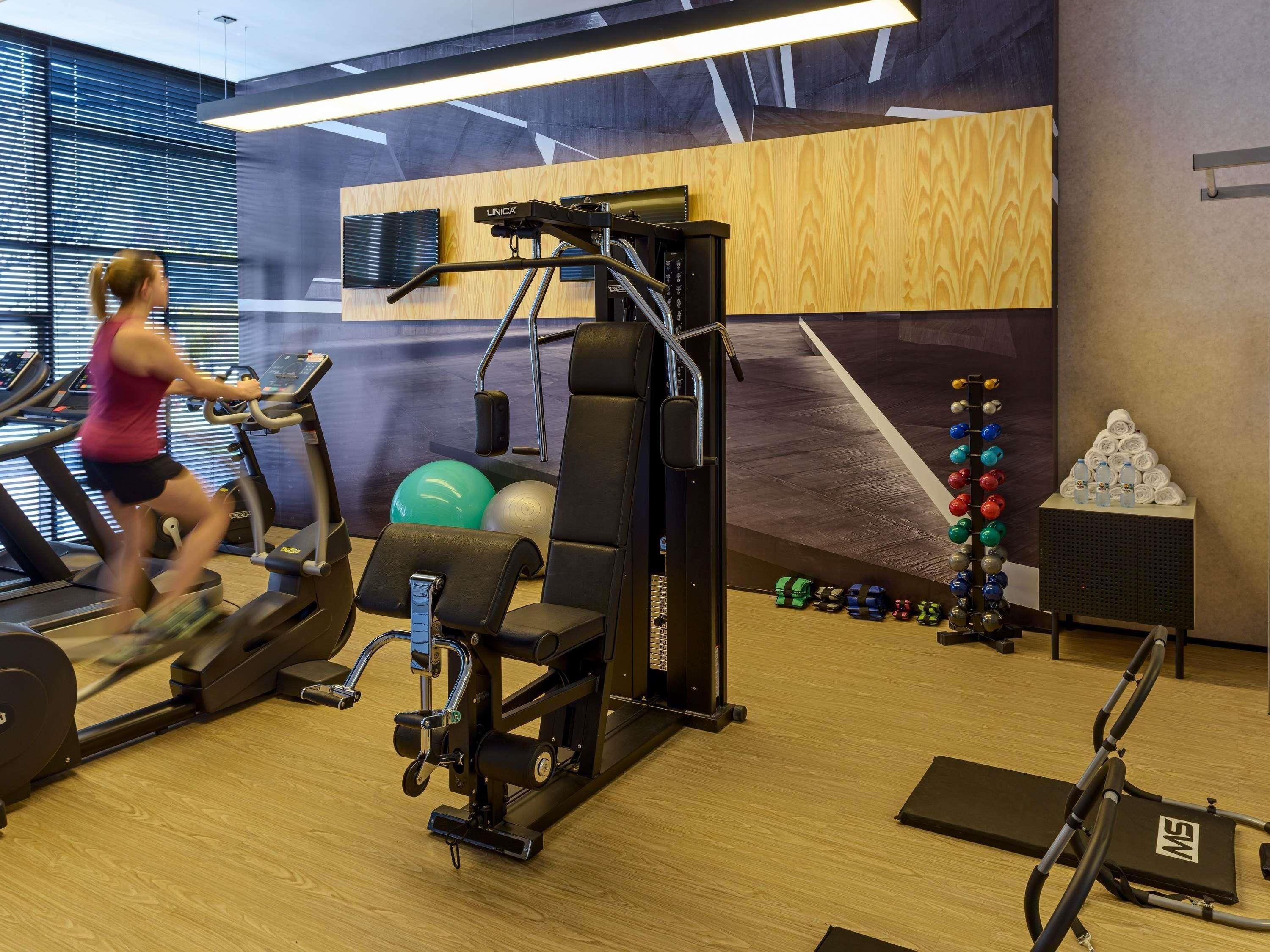 A gym with exercise equipment, a treadmill, and a wall-mounted TV.