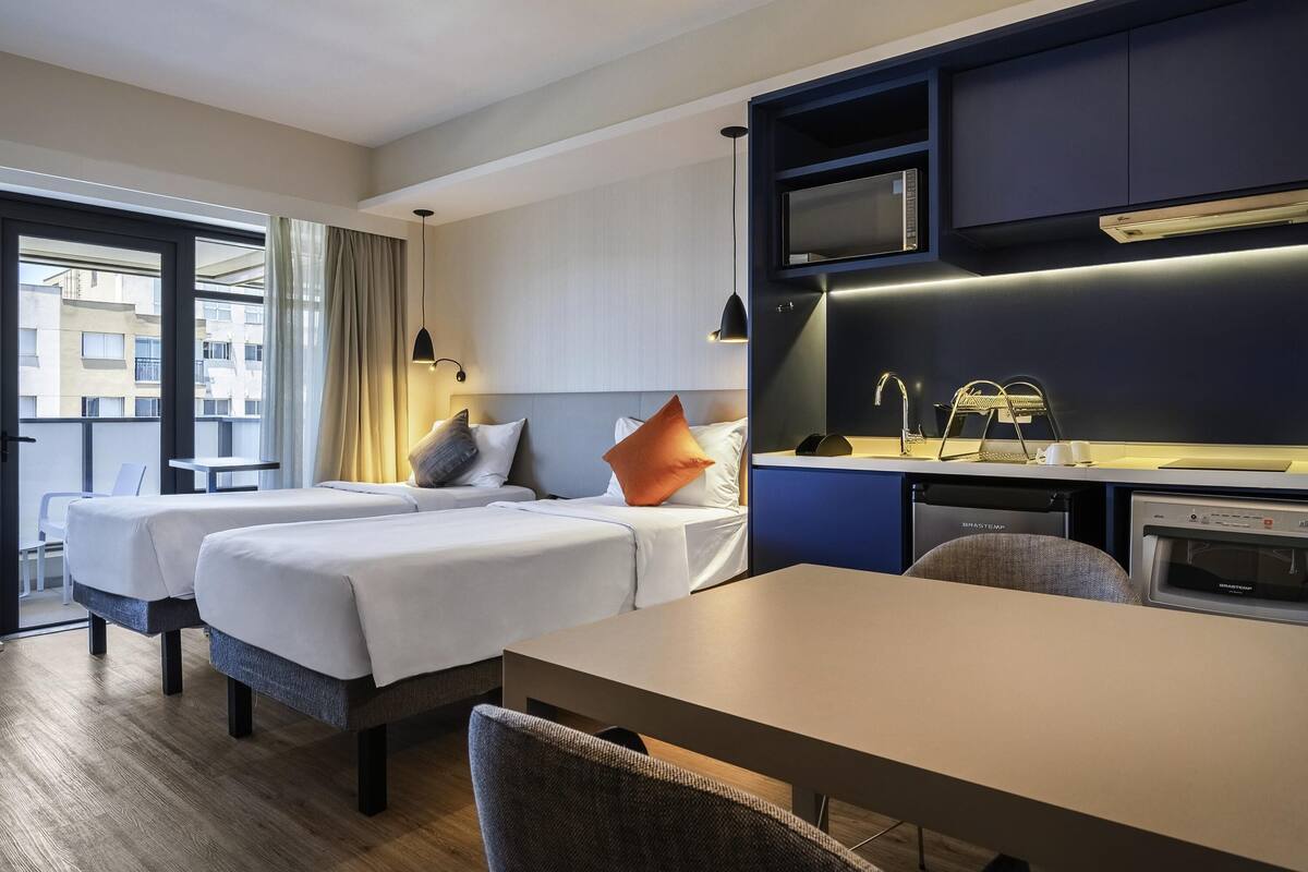 Ein Hotelzimmer mit zwei Betten, einem Esstisch, einer Mikrowelle und einem Waschbecken.