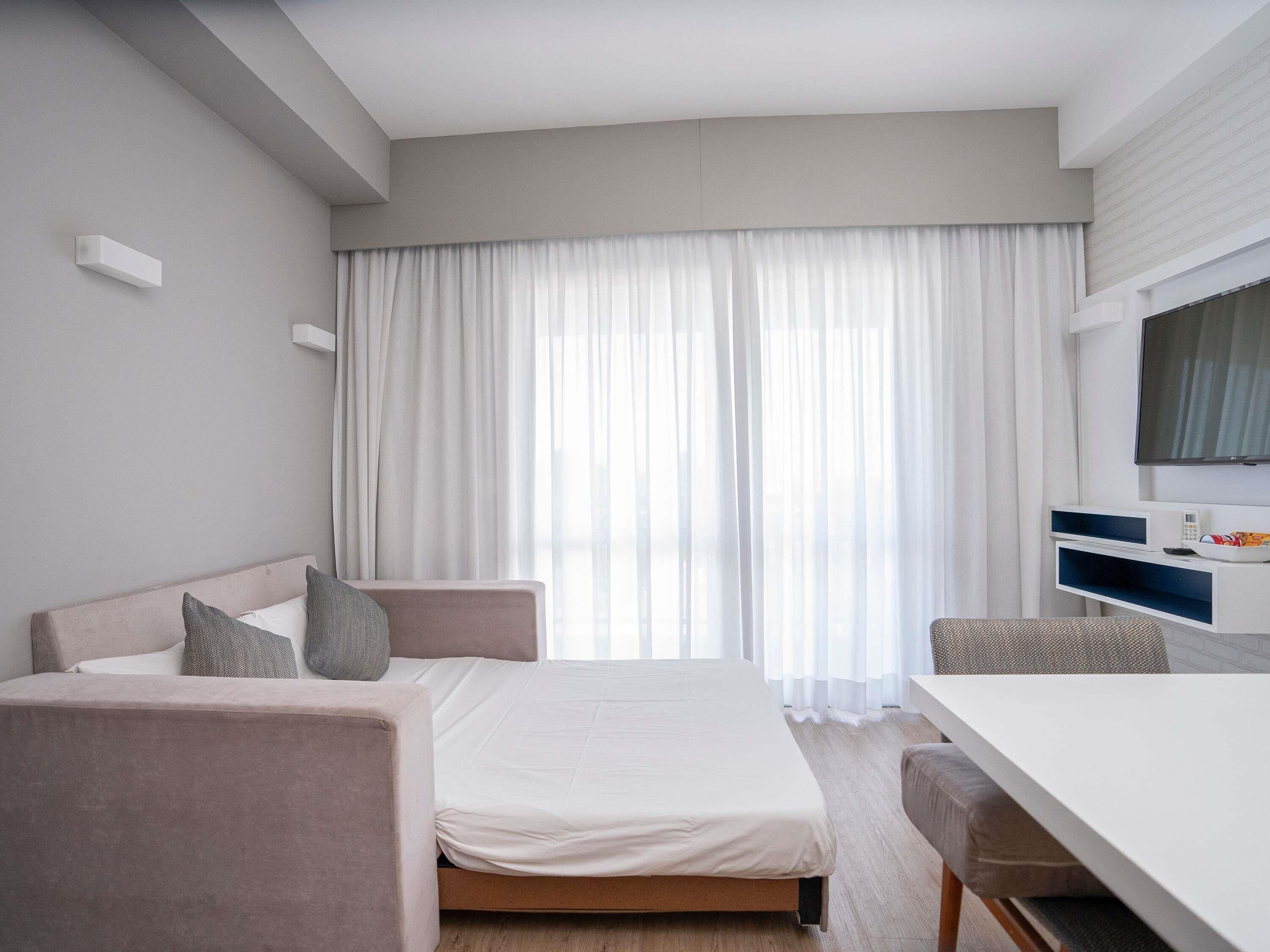 Quarto de hotel moderno com cama, escrivaninha e televisão.