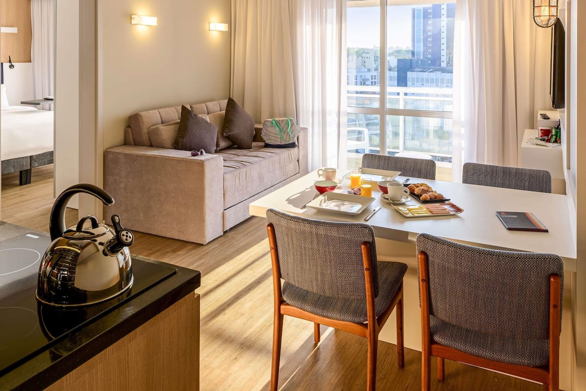 Une chambre d’hôtel moderne dotée d’un coin repas, d’un canapé et offrant une vue sur la ville.