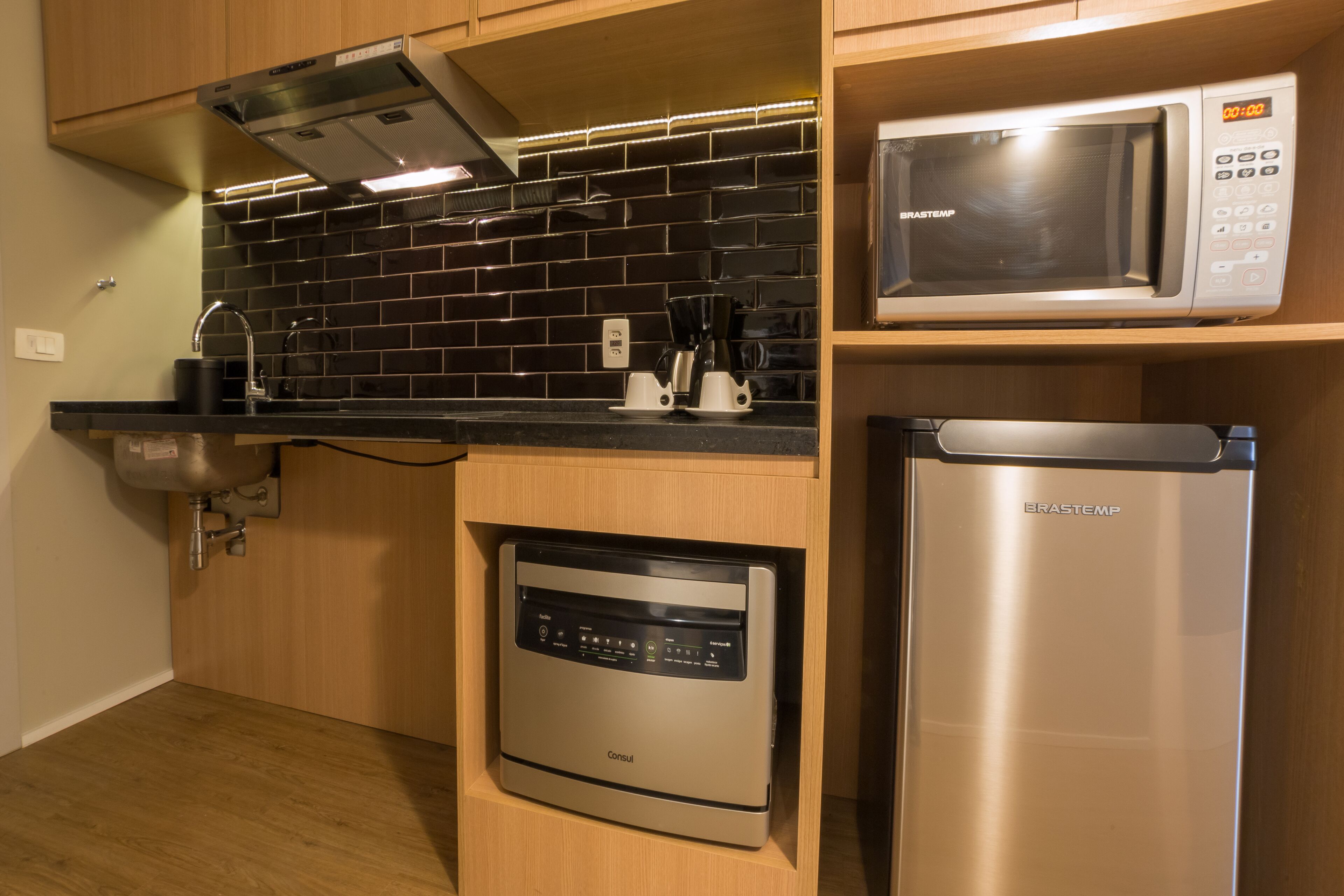 A compact kitchen with a dishwasher, a microwave, and a coffee maker on the countertop.
