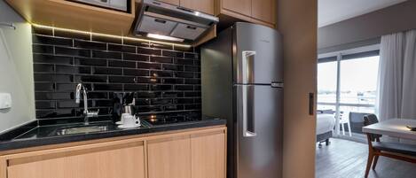 Una cocina moderna con un refrigerador de acero inoxidable, un microondas y un horno empotrado.