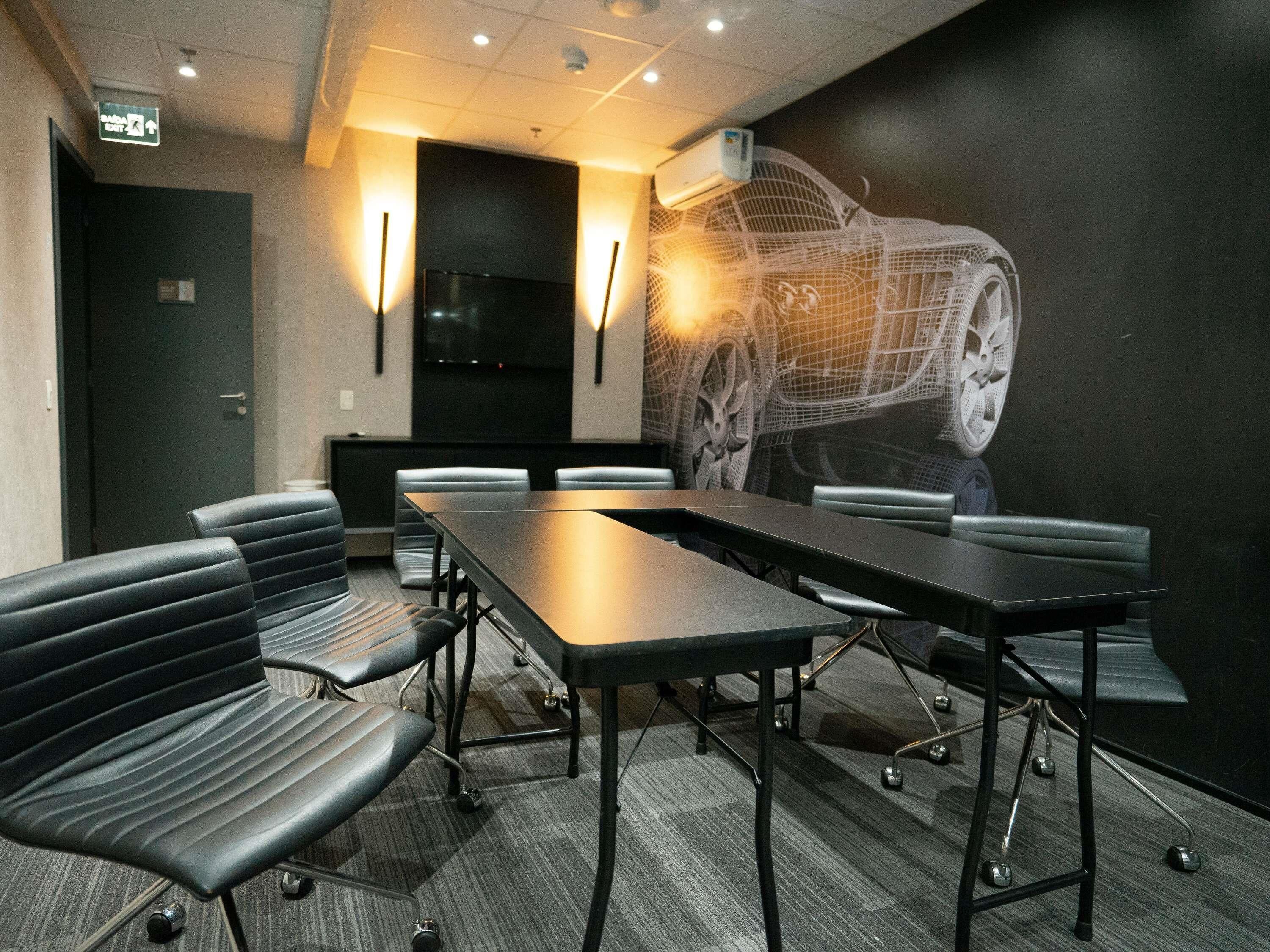Une salle de conférence avec une longue table, des chaises et une fresque murale représentant une voiture.