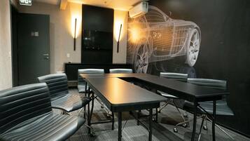 Une salle de conférence avec une longue table, des chaises et une fresque murale représentant une voiture.