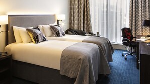 Une chambre d’hôtel avec deux lits, un bureau et une chaise.