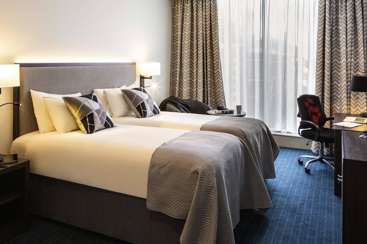 Een hotelkamer met twee bedden, een bureau en een stoel.