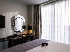 A hotel room with a bed, desk, chair, and a large window with curtains. - Mercure Bridgwater Hotel (Bridgwater)