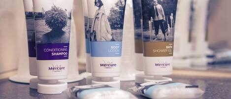 Three bottles of Mercure hotel toiletries: conditioning shampoo, body lotion, and shower gel.