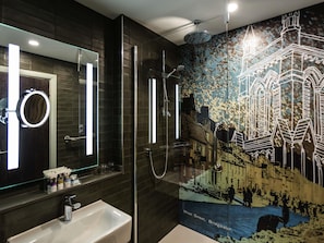 Un baño moderno con un espejo grande, un lavamanos y una ducha.