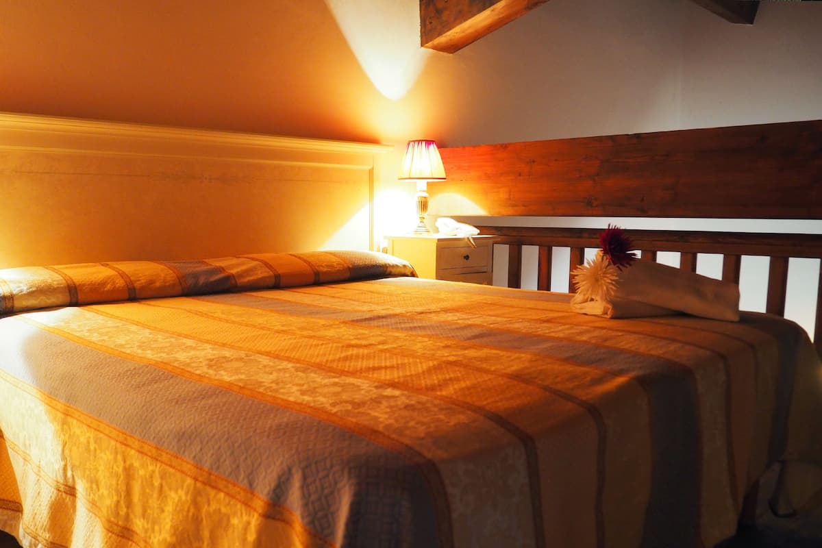 A neatly made bed with a striped bedspread, a bedside lamp, and a wooden headboard.