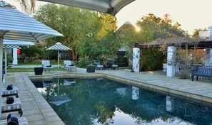 Una piscina al aire libre, sombrillas, sillones reclinables de piscina