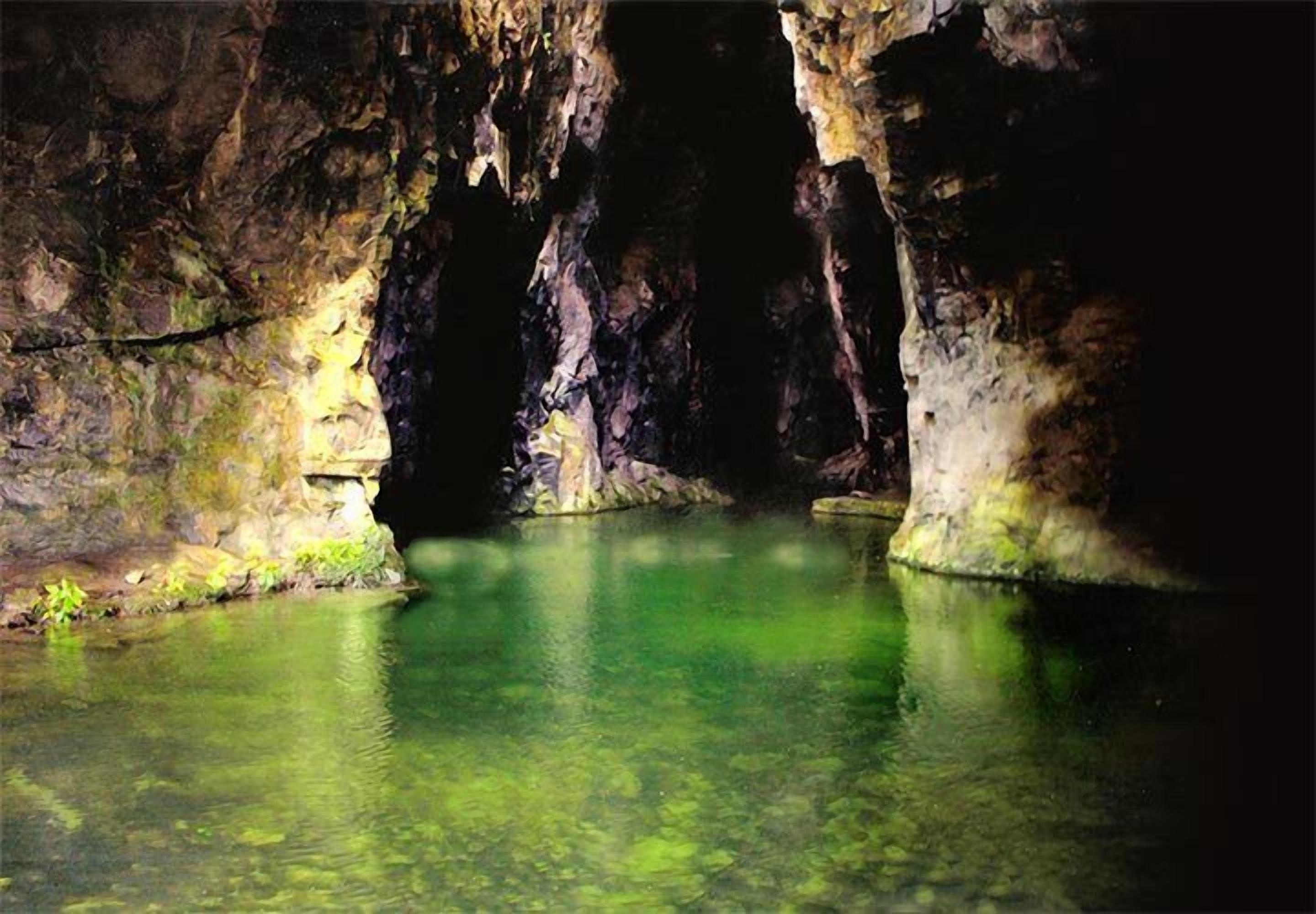 Une grotte abritant un bassin d’eau claire, entourée de parois rocheuses.