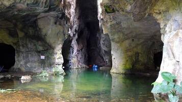 Una cueva con una piscina de agua cristalina y un kayak azul.