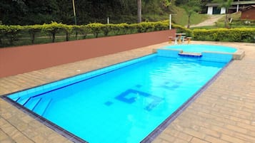 Een buitenzwembad, ligstoelen bij het zwembad