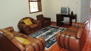 A living room with leather sofas, a television on a stand, and a patterned rug. - Pousada Gruta do Anjo (Socorro)