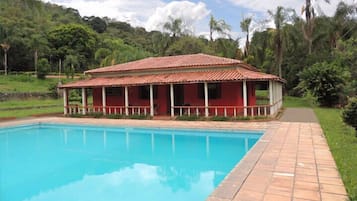 Een buitenzwembad, ligstoelen bij het zwembad