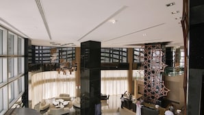 Un moderno vestíbulo de hotel con un mostrador de recepción curvo, zona de estar y un gran muro decorativo.