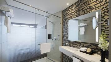 A modern bathroom with a glass-enclosed shower, a vanity with a mirror, and a decorative tile backsplash.