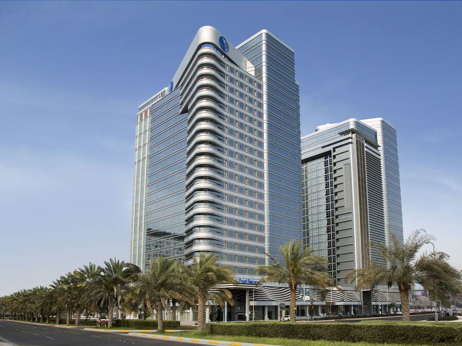 A modern high-rise hotel with a curved facade, multiple floors, and a prominent entrance with a covered area.