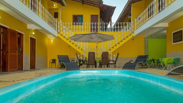 Una piscina con sillones de descanso y una mesa, rodeada de paredes amarillas y una escalera.