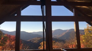A cabin with a large window offering a view of autumnal mountains. - Secluded mountain cabin 5 acres , all rooms with view,  hear soothing waterfall (Maggie Valley)