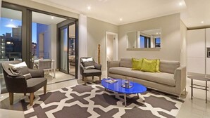 Una sala de estar moderna con sofá, sillones, una mesa de centro y un tapete estampado.