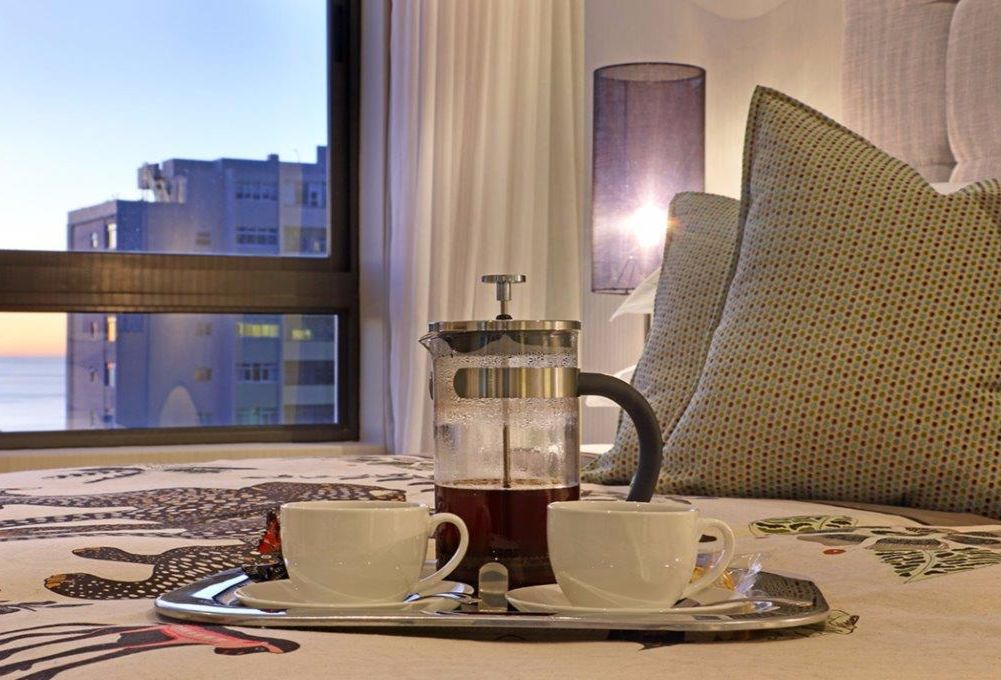 Ein Zimmer mit einem Bett, einer Kaffeemaschine, zwei Tassen und einem Tablett.